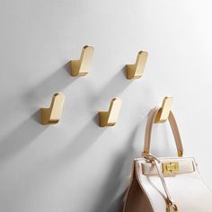 a handbag hanging on the wall next to three hooks