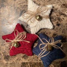 three knitted stars with bells tied to them sitting on a marble slabd surface