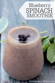 blueberry spinach smoothie in a glass on a table with spinach leaves