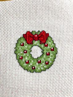 a cross stitch christmas wreath with red bows