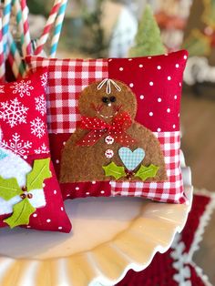 two decorative christmas pillows sitting on top of a plate