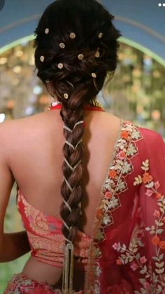 the back of a woman's head with long braids and gold jewelry on it