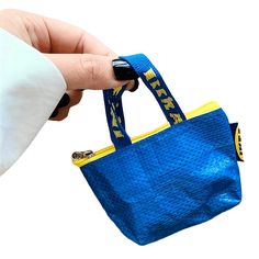 a hand holding a blue bag with yellow handles