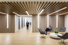 two people are walking in an office with wood slats on the walls and floor