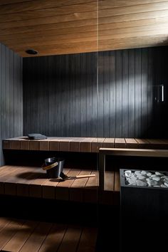 an empty sauna room with wooden floors and black walls is pictured in this image