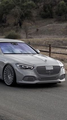 a silver car driving down a road next to a fence