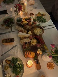 a table filled with lots of food next to candles and plates on top of it