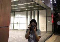 a woman taking a photo with her camera in front of an office building at night