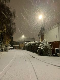 a snow covered street at night with the lights on