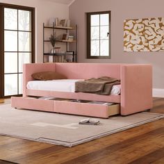 a pink day bed sitting on top of a wooden floor