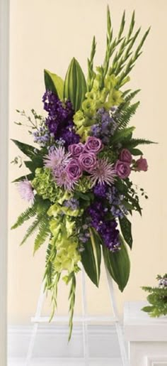 a bouquet of flowers sitting on top of a white stand in front of a wall