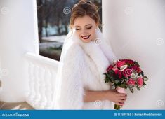 a beautiful young woman in white fur coat holding a bouquet of flowers and smiling at the camera