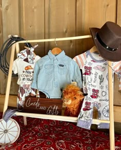 a baby's clothing display on a wooden stand with cowboy hats and other items