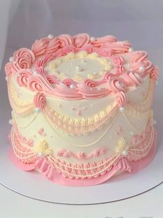 a pink and white decorated cake on a plate