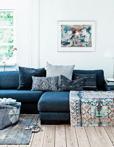 a living room with blue couches and rugs on the wooden floor next to a window