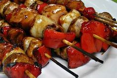 several skewers of meat and vegetables on a white plate