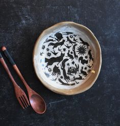 a black and white plate with two spoons on it next to a wooden utensil