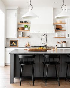 two black chairs are at the center of this kitchen island