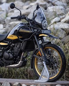 a black and yellow motorcycle parked next to some rocks