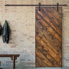 an open wooden door sitting next to a bench in front of a white brick wall