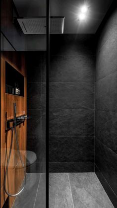 a black and white photo of a shower in a bathroom with wood paneling on the walls