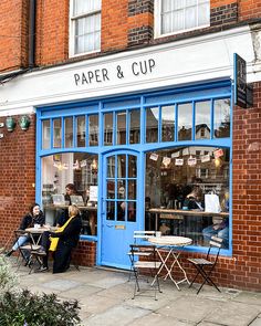 people sitting at tables in front of a paper and cup shop