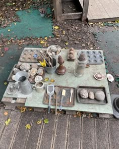 an outdoor table with pots, pans and utensils laid out on it