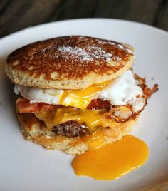 a breakfast sandwich with eggs and bacon on a white plate