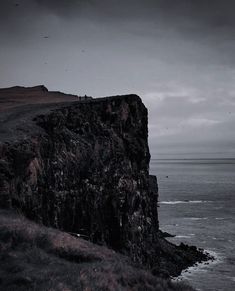 a black and white photo of a cliff by the ocean