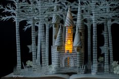 an open book with a castle made out of paper on top of it and trees in the background