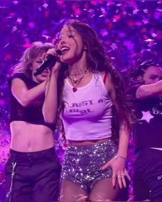 two girls singing on stage with confetti in the background