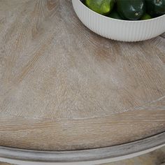 a bowl of limes sitting on top of a wooden table