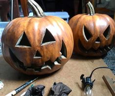 two carved pumpkins sitting on top of a table next to a pair of scissors