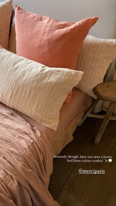 some pink and orange pillows on top of a bed