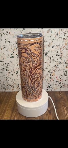 a brown and white vase sitting on top of a wooden table next to a wall