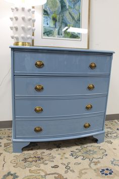 a blue dresser with brass handles and knobs on it's drawers in a living room