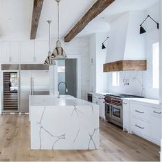 a large kitchen with white cabinets and marble counter tops, along with an island in the middle