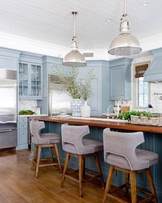 a kitchen with blue walls and wooden floors, two bar stools at the center