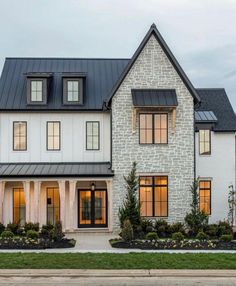 a large white house with black roof and two story windows on the side of it