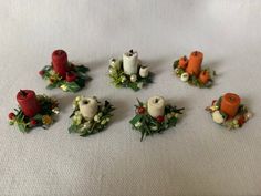 small christmas decorations are arranged on a white tablecloth with red and orange candlesticks