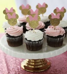 cupcakes with pink frosting and gold minnie mouse toppers on a cake plate