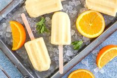 popsicles with oranges and mint on top of an ice tray next to two forks