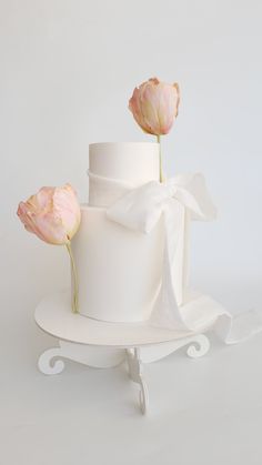 a three tiered cake with two flowers on the top and one flower sticking out of it