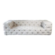 a white couch sitting on top of a white floor next to a chair and ottoman