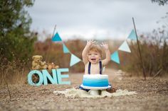 a young boy sitting on top of a cake in the middle of a dirt field