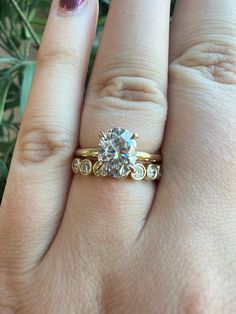 a woman's hand with a ring on it and a flower in the background