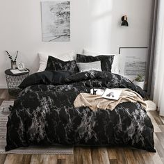 a black and white bedroom with wood flooring in the room, bedding is made up