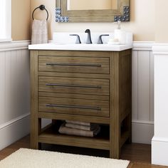 a bathroom vanity with two drawers and a mirror above it, in front of a white rug