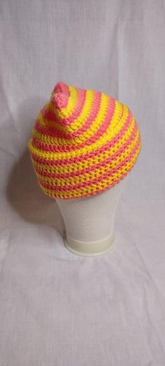 a yellow and pink hat sitting on top of a white mannequin head