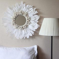 a bedroom with a bed, lamp and mirror on the wall above it's headboard